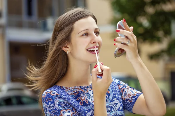 Joven guapa morena tiñe tus labios con un pincel — Foto de Stock