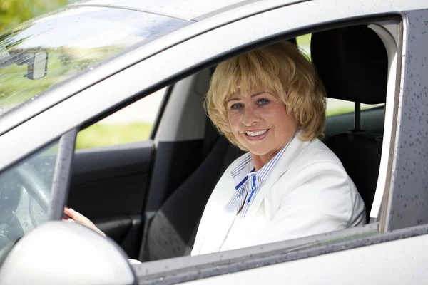 Old happy elderly driver woman 55-60 years in jacket Driving a C — Stock Photo, Image