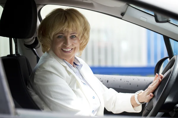 Viejo feliz anciano conductor mujer 55-60 años en chaqueta Conducción de una C —  Fotos de Stock