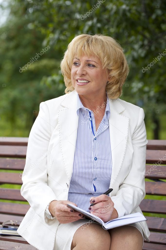 Portrait of serene mature woman in the summer park 