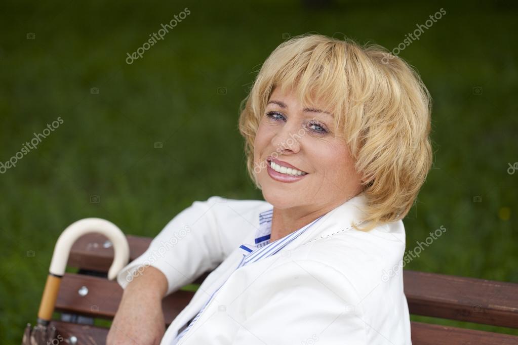 Portrait of lovely middle aged woman in the summer park 