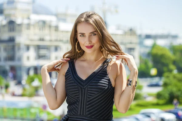 Jonge mooie vrouw in zwarte jurk poseren buitenshuis in zonnige we — Stockfoto