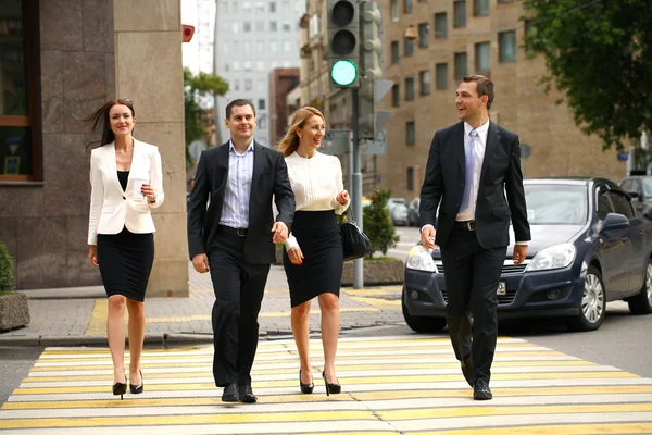 Quatre hommes d'affaires prospères traversant la rue dans la ville — Photo