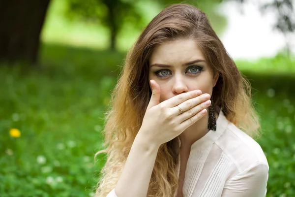 Junge schöne Mädchen bedeckt ihren Mund mit seiner Hand — Stockfoto