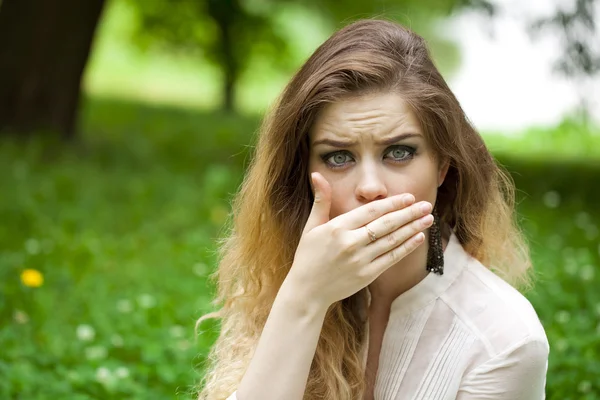 Junge schöne Mädchen bedeckt ihren Mund mit seiner Hand — Stockfoto