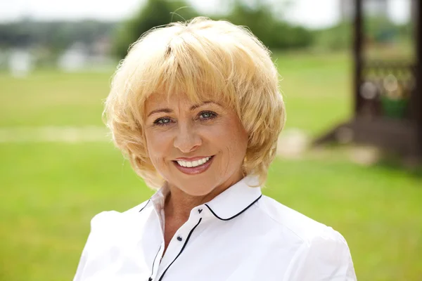 Portrait of an elderly woman in a white jacket on the background — Stock Photo, Image