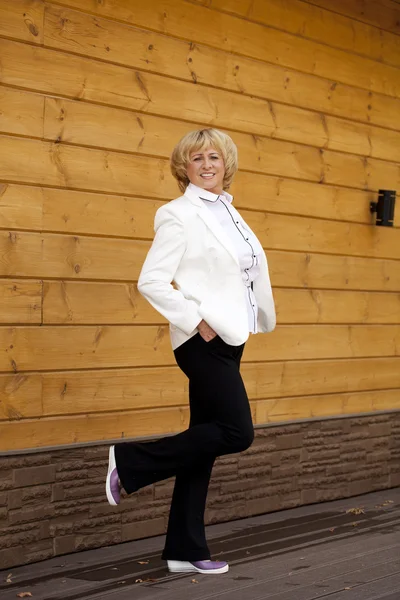 Portrait d'une femme âgée vêtue d'une veste blanche sur le fond — Photo