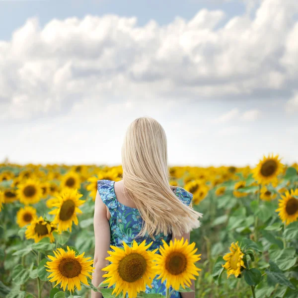 Portret van een mooie jonge blonde vrouw in blauwe jurk op een ba — Stockfoto