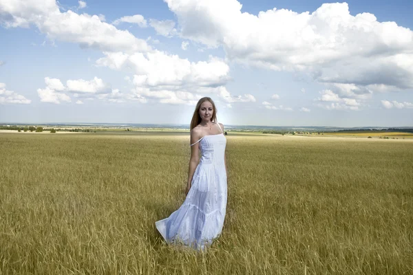 Young beautiful woman in a long white dress is standing in a whe