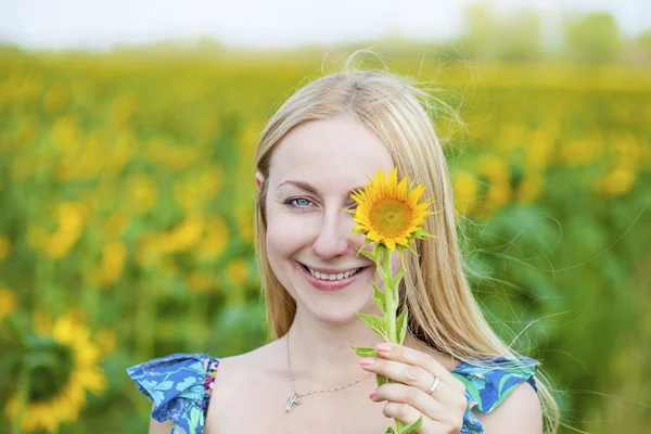 Portret van een mooie jonge blonde vrouw in blauwe jurk op een ba — Stockfoto