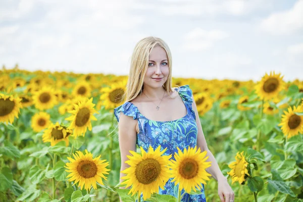 Portret van een mooie jonge blonde vrouw in blauwe jurk op een ba — Stockfoto