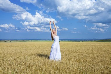 Young beautiful woman in a long white dress is standing in a whe