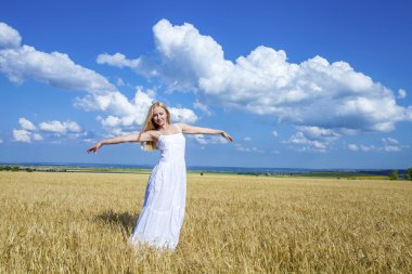 Young beautiful woman in a long white dress is standing in a whe
