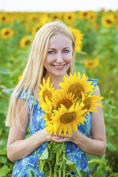 Portret van een mooie jonge blonde vrouw in blauwe jurk op een ba — Stockfoto