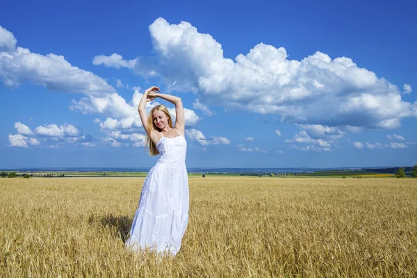 Young beautiful woman in a long white dress is standing in a whe — Stockfoto