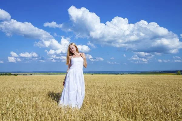 Joven hermosa mujer en un vestido blanco largo está de pie en un whe — Foto de Stock