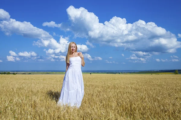 Young beautiful woman in a long white dress is standing in a whe — ストック写真