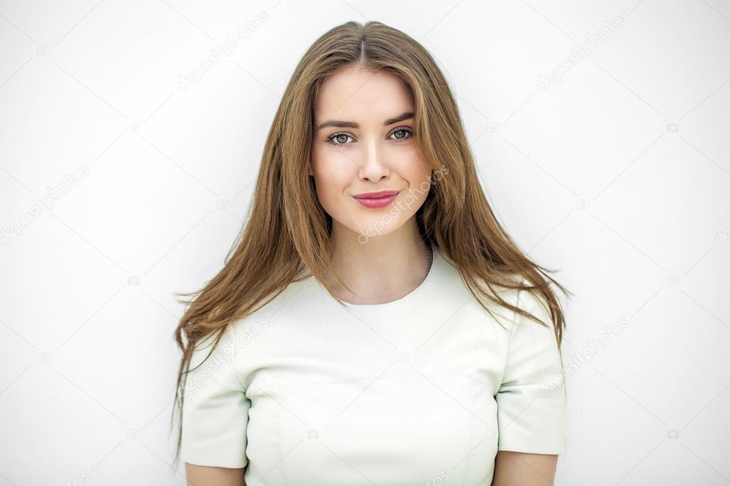 Beautiful young happy woman posing against a white wall