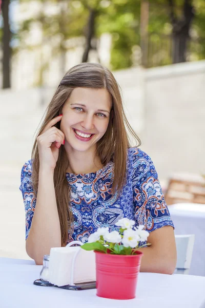 Menina morena bonita feliz sentada em uma cafeteria — Fotografia de Stock