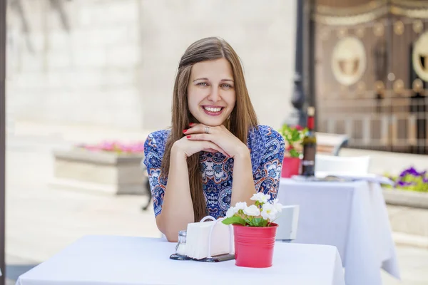 Menina morena bonita feliz sentada em uma cafeteria — Fotografia de Stock