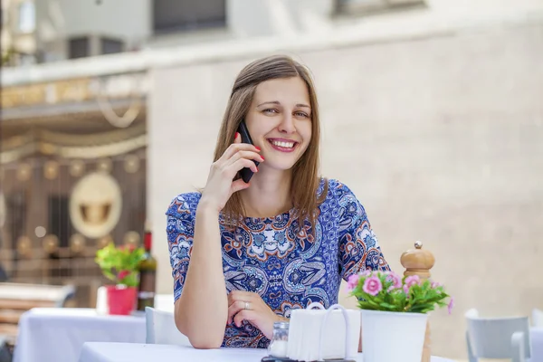 Gelukkig mooie brunette meisje zit in een koffieshop — Stockfoto