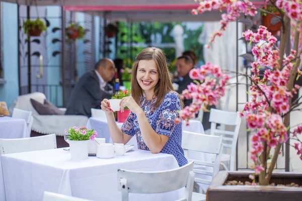 Menina morena bonita feliz sentada em uma cafeteria — Fotografia de Stock