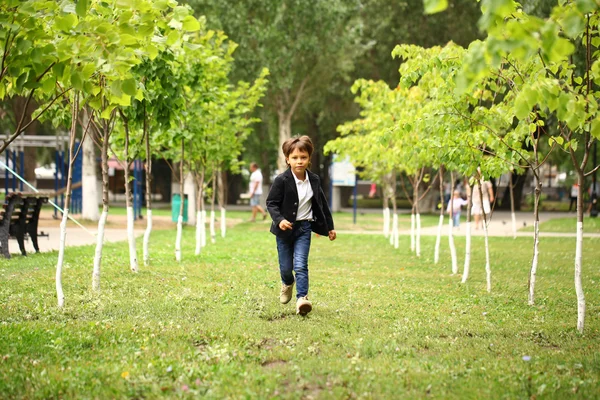 Glad liten brunett pojke körs i en sommar park — Stockfoto