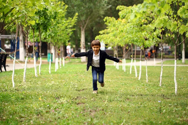 Menino morena feliz corre em um parque de verão — Fotografia de Stock