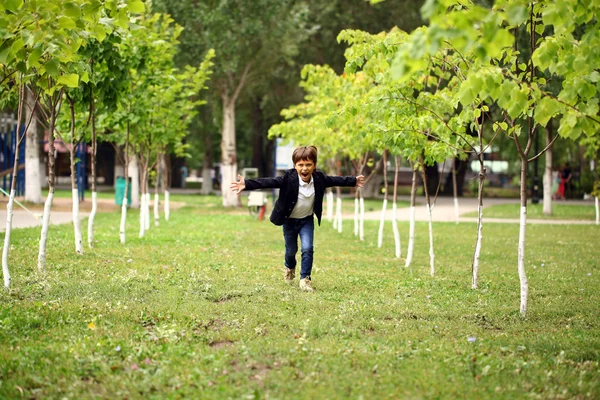 Happy little brunette boy runs in a summer park — Stock Photo, Image