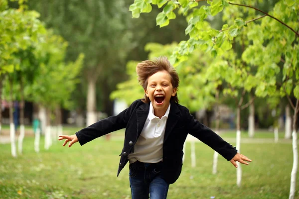 Menino morena feliz corre em um parque de verão — Fotografia de Stock