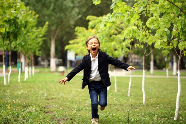 Happy little brunette boy runs in a summer park — Stock Photo, Image