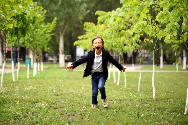 Happy little brunette boy runs in a summer park — Stock Photo, Image