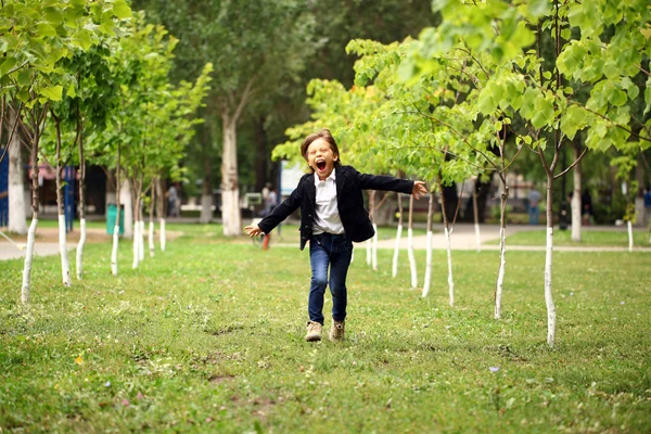 Glad liten brunett pojke körs i en sommar park — Stockfoto