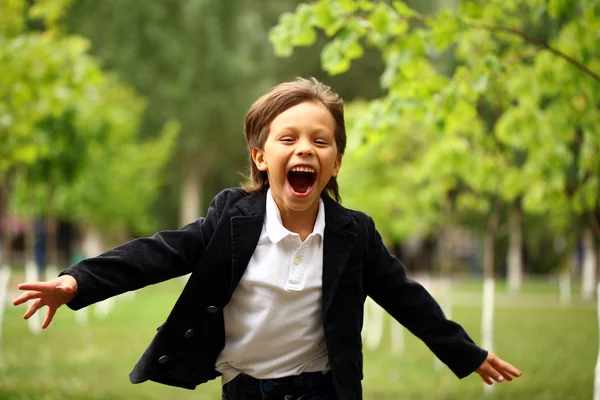 Happy little brunette boy runs in a summer park — Stock Photo, Image