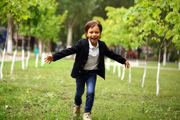 Joyeux petit garçon brune court dans un parc d'été — Photo