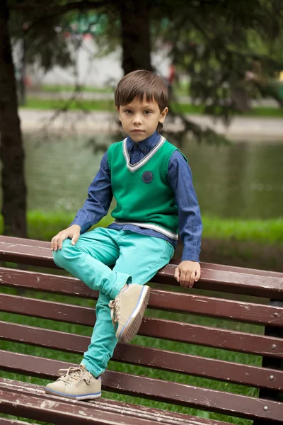 Little boy sitting on a bench in a summer park — Stock Photo, Image