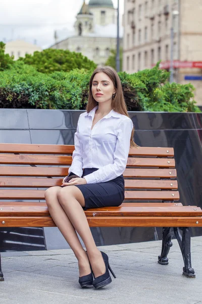 Mulher de negócios bonita sentada em um banco — Fotografia de Stock