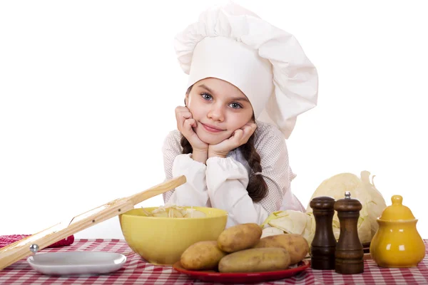 Vackra lilla chef spis på skrivbordet med grönsaker — Stockfoto