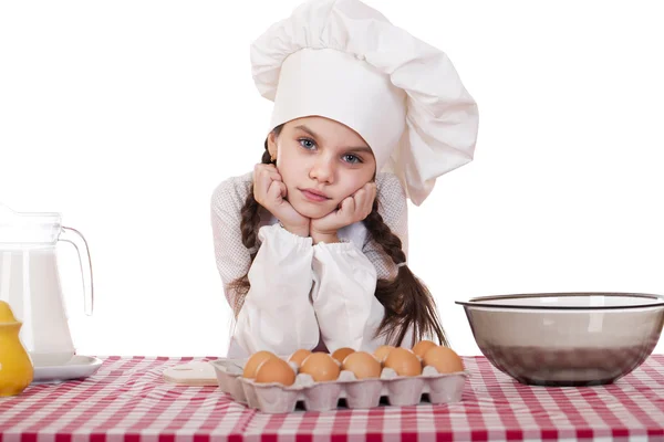 Little girl in a white apron near the box with eggs — Stock Photo, Image