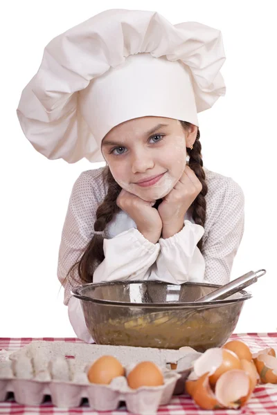 Bambina in grembiule bianco si rompe vicino al piatto con le uova — Foto Stock