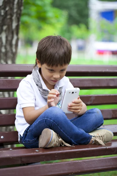 Μικρό αγόρι παιχνίδια με προσήλωση στο smartphone — Φωτογραφία Αρχείου