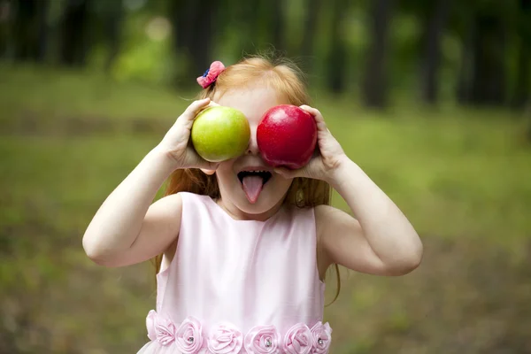 Zrzavá holčička v růžových šatech drží dvě jablka — Stock fotografie