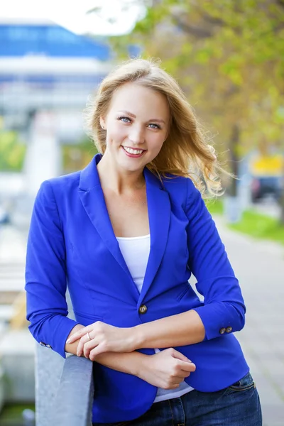 Schöne junge Blondine in einer blauen Jacke — Stockfoto