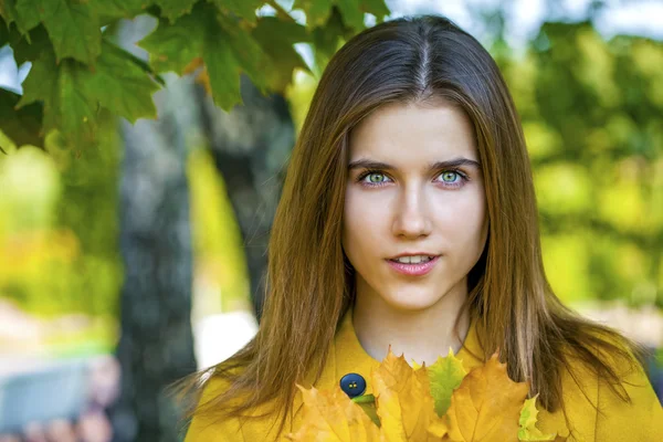 Happy young woman in yellow coat in autumn park — Stock Photo, Image