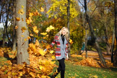 Happy woman drop up leaves in autumn park  clipart