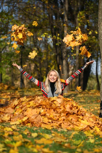 Щаслива жінка опускає листя в осінній парк — стокове фото