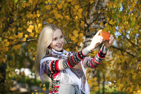 Szczęśliwy, piękna dziewczyna sfotografowany na telefon komórkowy w parku jesień — Zdjęcie stockowe