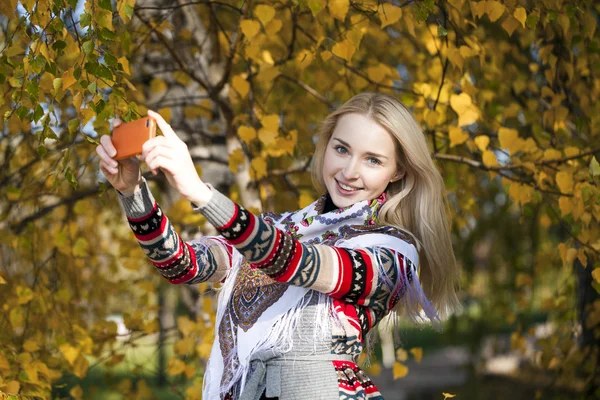 Šťastná, krásná dívka fotografoval na mobil v podzimním parku — Stock fotografie