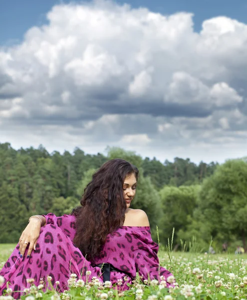 Retrato de uma jovem sentada em um gramado verde — Fotografia de Stock