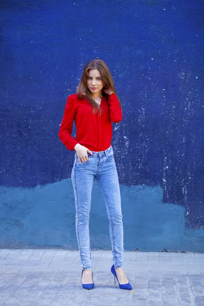 Krásná mladá dívka v džínách a červené tričko na pozadí, vyřešit hádank — Stock fotografie